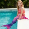 Queue de sirène Vampire pour Fille portée par une fillette assise au bord d'une piscine, queue dans l'eau
