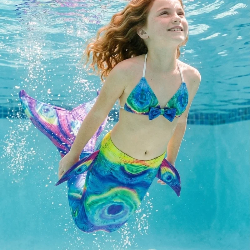 Queue de sirène des Abysses portée par une fillette en mouvement sous l'eau, rayons de soleil