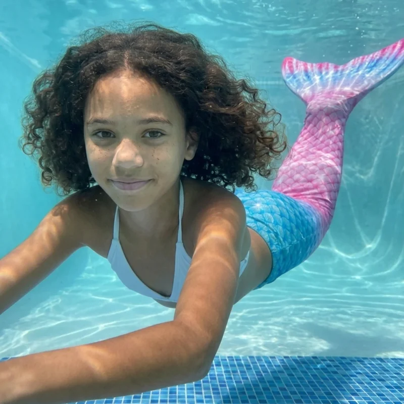 Queue de sirène Rose et Bleue Multicolore portée par une fillette en mouvement sous l'eau, rayons de soleil