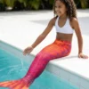 Queue de sirène Rouge Arista portée par une fillette de profil au bord d'une piscine ensoleillée
