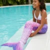 Queue de sirène Ursula Enfant portée par une fillette assise au bord d'une piscine, queue dans l'eau