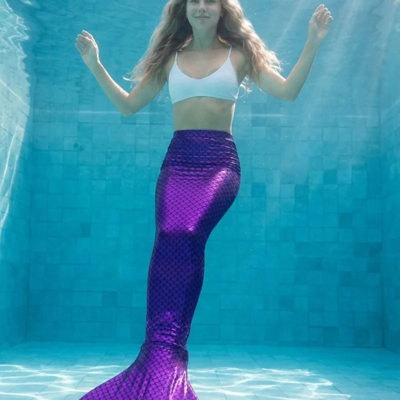 Queue de sirène Violette Alana portée par une jeune femme en mouvement sous l'eau, rayons de soleil